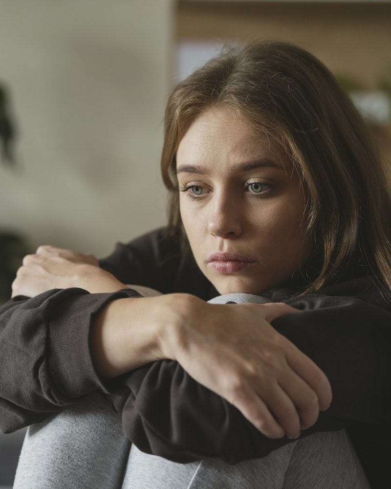 Caucasian sad woman sitting at the sofa with depression